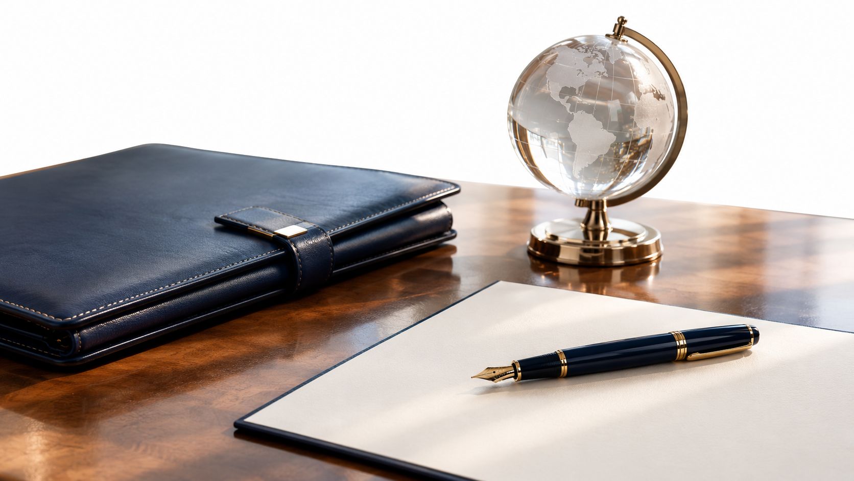 A leather planner, glass globe, and fountain pen sit on a polished wooden executive office desk.